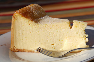 Slice of cheesecake on white plate with fork
