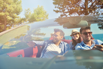leisure, road trip, travel and people concept - happy friends driving in cabriolet car along...