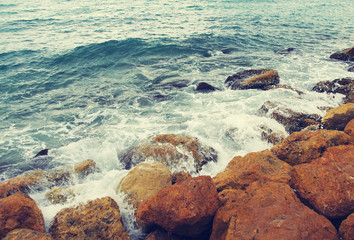 Sea and stones, toned. Strong waves lap about stones