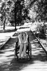 sad adult woman on wheelchair in the park