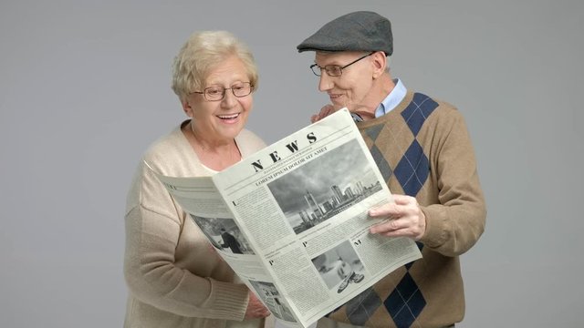 Elderly man and women reading a newspaper