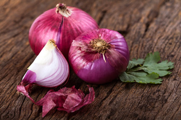 Close up of the  sliced red onion and whole bulb onion on a wooden background © Cozine