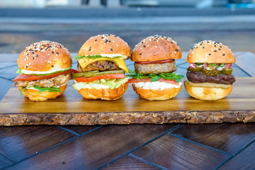Four burgers on wooden board in restaurant