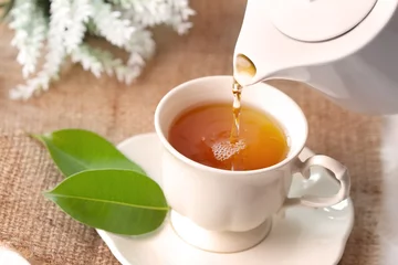 Photo sur Plexiglas Theé Close up pouring hot black tea in a white tea cup ,  Tea ceremony time concept