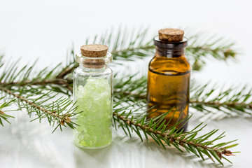 Obraz na płótnie Canvas Bottles of essential oil and fir branches for aromatherapy and spa on white table background