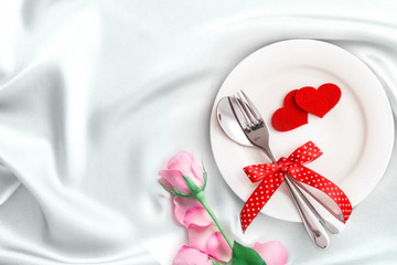 red heart shape with White empty plate with fork and spoon on white silk fabric for love dinner concept