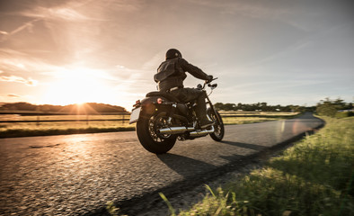 Obraz premium Mężczyzna jedzie sportster motocykl podczas zmierzchu.
