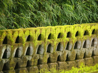 Close view of an old weathered asian stone wall covered with moss