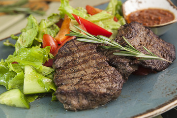 Pieces of meat medallions and vegetables on a plate, grilled beef