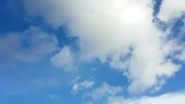 Time lapse white clouds over blue sky.