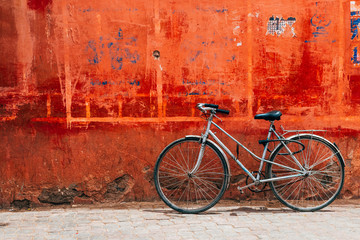 old bike standing at colorful red wall