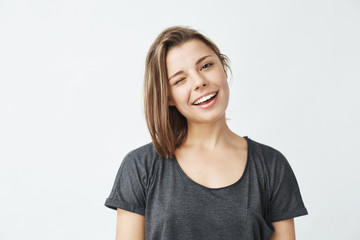 Cheerful young beautiful girl smiling winking looking at camera over white background.