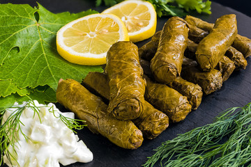 Delicious stuffed grape leaves (the traditional dolma of the mediterranean cuisine) on black dish...