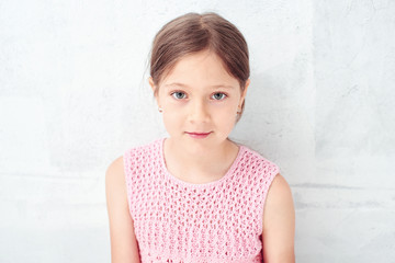 Portrait of a little girl on the white background of the wall
