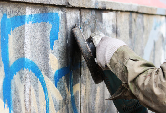 Removal of graffiti on a concrete wall of an underground passage with the help of a angle grinder.