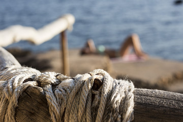 Kamienista plaża w Chorwacji z perspektywy drewnianej poręczy / Kobieta w tle - obrazy, fototapety, plakaty