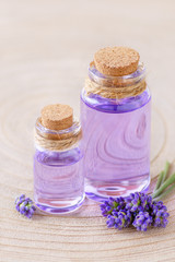 Fototapeta na wymiar lavender oil in glass bottles and fresh lavender flowers on stump and wooden background