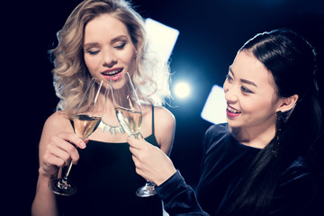 smiling seductive glamour multiethnic girls toasting with champagne glasses and spending time at party