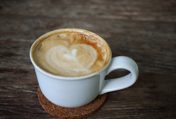 coffee with heart in a white cup on wooden background