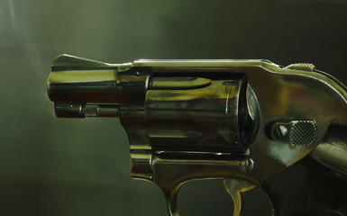 revolver gun with smoke floating in the air after shoot on black background