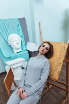 Woman leaning against an easle in an art room