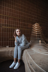 Fototapeta premium Young woman leaning against art sculpture