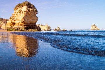 A view of the tide coming in from the rocky beach in Lagos, Portugal during sunset