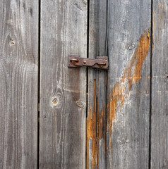 Small iron rusty latch on a mouldering wooden door