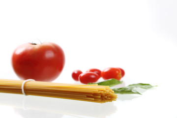 Raw spaghetti noodle with tomatoes and basil isolated in white background