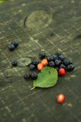 Ripe blueberries and strawberries lie on a wooden table