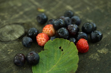 Ripe blueberries and strawberries lie on a wooden table
