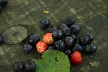 Ripe blueberries and strawberries lie on a wooden table