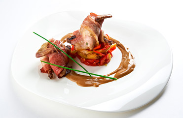 Roasted quail with saute from vegetables and sauce isolated on white background