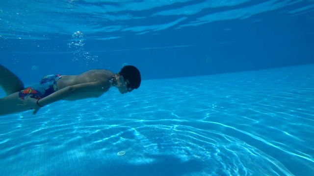 Portrait of the happy teenager swimming underwater and smiling to camera