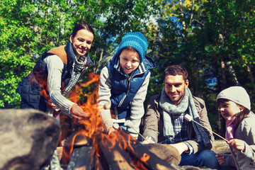 happy family roasting marshmallow over campfire