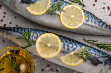 Fresh raw fish closeup. Mackerel with salt, lemon and spices on grey background. Cooking fish with herbs. Top view