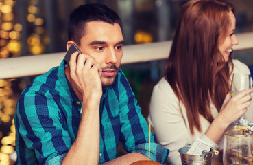 man with smartphone and friends at restaurant