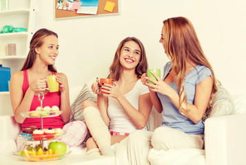 happy young women drinking tea with sweets at home