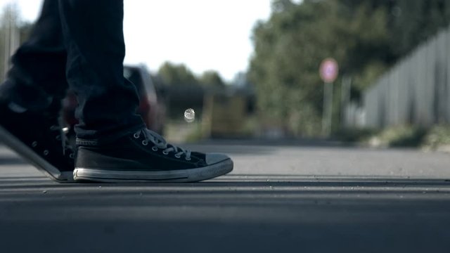 A shot of a pair of sneakers moonwalking while traffic passes by in the background. Filmed on a sunny day from a ground perspective.