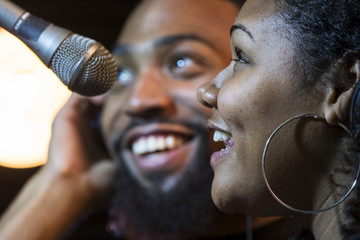 Black male and female singing in a recording studio - obrazy, fototapety, plakaty