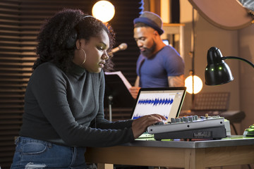 Black male vocalist working with sound engineer in a recording studio
