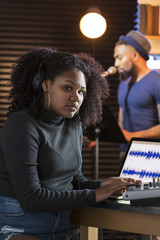 Black male vocalist working with sound engineer in a recording studio