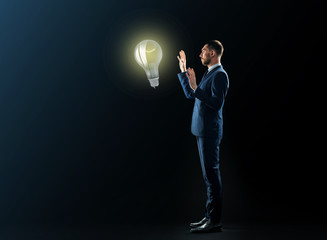 businessman with lightbulb over black background