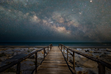 Wooden bridge walkway to the beach with milky way galaxy - Powered by Adobe