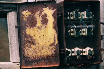 Old broken switchboard On a wooden wall .disassembled, plundered electrical switchboard. shield, control panel of equipment operation. Peeling paint resembles a fairy tale animal Industrial trash