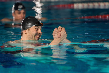 Close up of happy male swimmer shaking another swimmers hand