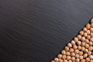Chickpeas lies on a black stone board, space for text, black background