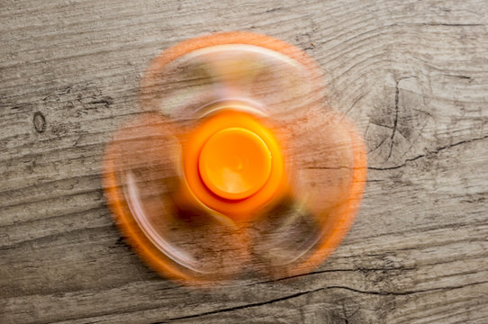Close up shot of an orange fidget spinner while spinning