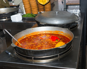 Spicy soup with peppers in large cauldron with ladle inside