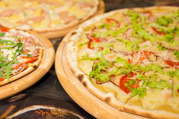 Delicious tasty pizzas with variety of toppings and cheese on wooden trays